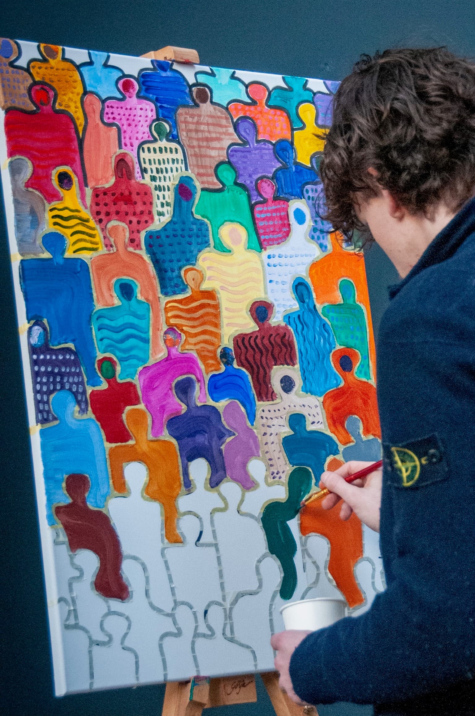 Thibault painting a colorful crowd of faceless figures