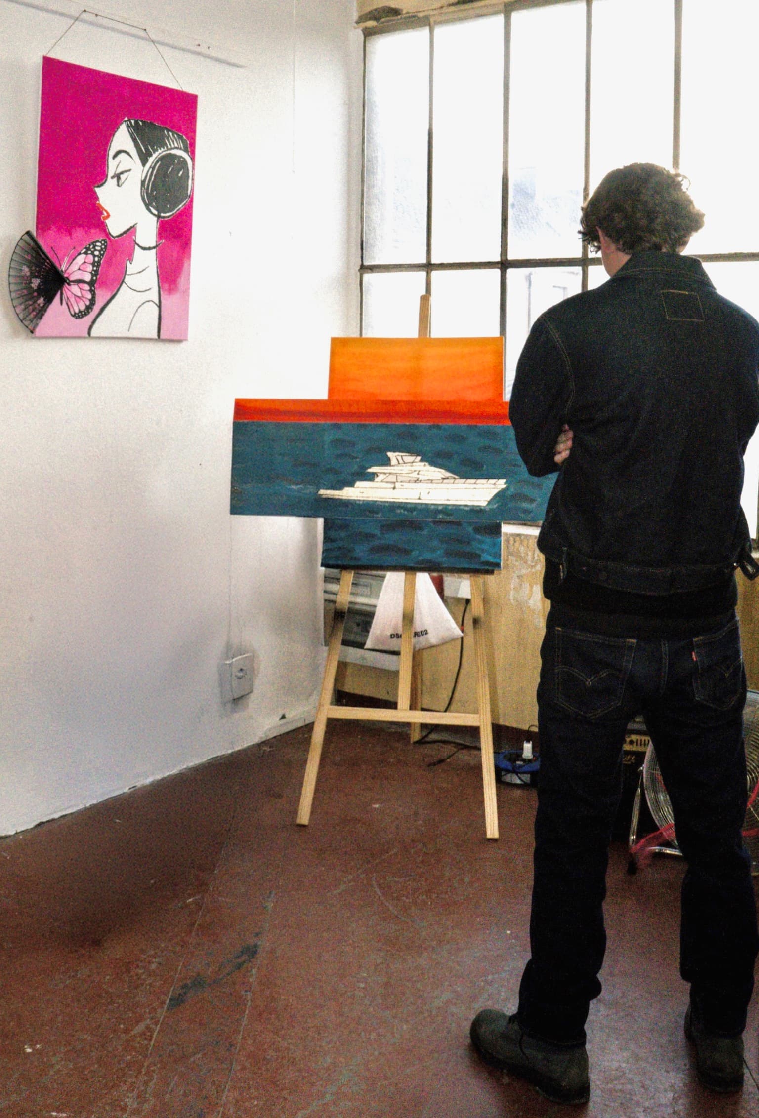 Thibault standing in studio looking at a boat painting